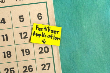 Fertilizer application schedule in farming and agriculture concept. Written reminder note on...