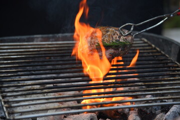 BBQ Barbecue grilled meat stick on fire flame with hot charcoal cooking outside. Beef grilling picnic outdoor with smoke bacon spicy sausage for party. Grill pork bbq on fire flame