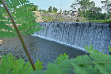 Water fall dam landscape view with green leaf natural frame and blue sky background