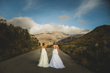pareja de mujeres casadas caminando por la mitad de la vía en sus vestidos de bodas en verano 