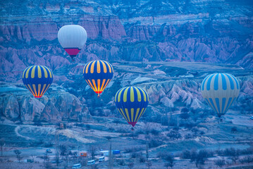 Sunrise in Cappadocia with colorful hot air balloons fly in sky over canyons, valleys morning...