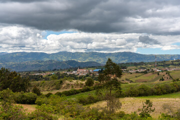 Church in a town seen in the distance surrounded by country landscape with mountains in Colombia.