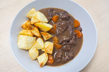 A plate of beef stew with potato.