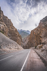 Road and river in a rocky gorge made of colored rocks in the Fan Mountains in Tajikistan