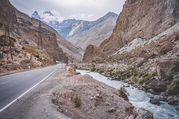 Road and river in a rocky gorge made of colored rocks in the Fan Mountains in Tajikistan
