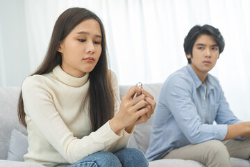 Stressed asian young couple man, woman quarrel on couch, relationship in trouble. Wife's hand...