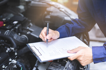 Auto check, car service shop concept. Automobile repairman writing job checklist on clipboard,...