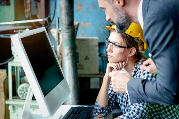 ฺฺBeautiful woman industrial engineer worker wears helmet and safety glasses using computer to...