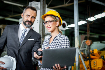 Young beautiful woman industrial engineer worker with helmet and safety glasses using laptop...