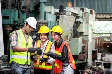 Group of male and female industrial engineer workers with helmet and safety vest inspecting engine at manufacturing plant industry factory. Worker working with machinery machine in industry workplace.