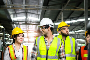 Group of industrial foreman engineer and workers with helmet and safety vest walking past to inspect machinery engine and production process at manufacturing industry factory. Teamwork at workplace