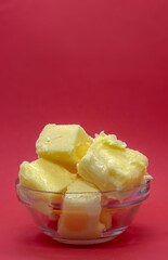 Closeup of Butter in a Small Glass Bowl Isolated on Red Background with Copy Space