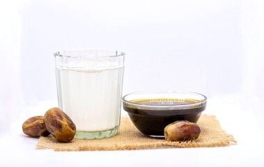 Date Palm Tree Juice or Khejur Ras in Glass with Phoenix Dactylifera Fruit and Liquid Date Palm Jaggery Isolated on White Background with Copy Space, Also Known as Date Palm Sap or Khejur Rosh