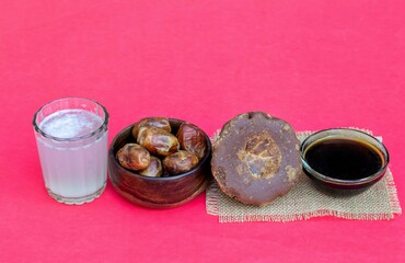 Date Palm Jaggery, Phoenix Dactylifera Fruit and Date Palm Tree Juice or Khejur Ras in Glass Isolated on Red Background with Copy Space, Also Known as Date Palm Sap or Khejur Rosh