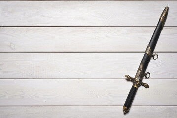 Vintage retro style dagger sword on the white wooden table background with copy space. Pirate table.