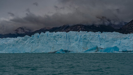 The amazing Perito Moreno Glacier. A wall of cracked ice rises above a glacial lake. Melted ice...