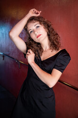 Caucasian female model posing in a red corridor.