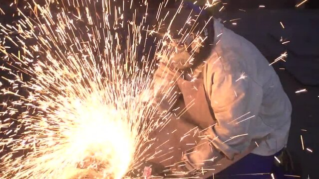 Locksmith works on metal processing with angle grinder with sparks in metallurgy.