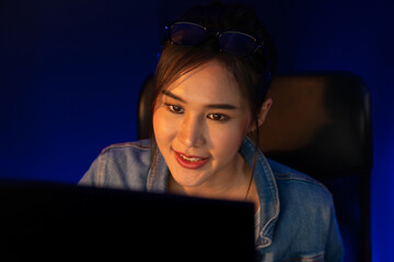 Smiling young beautiful asian creative officer looking on pc in sales target online, earning job's...