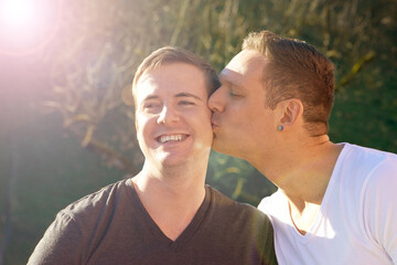 Gay couple, men and kiss in nature for love, affection and happy married people on honeymoon....