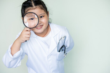 Cute girl asian in a medical play a doctor  .magnifying glass and portrait of a scientist girl in...