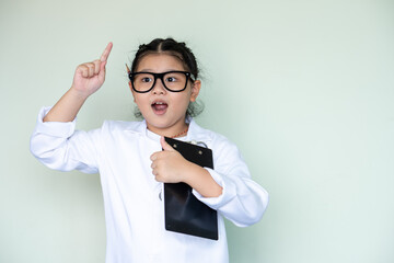 girl asian doctor surgeon pointing finger up looking inspired by genius thought showing good idea...