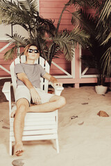 Early morning. A young attractive guy is relaxing near a bungalow.