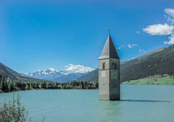 a tower in the middle of a lake with mountains in the background