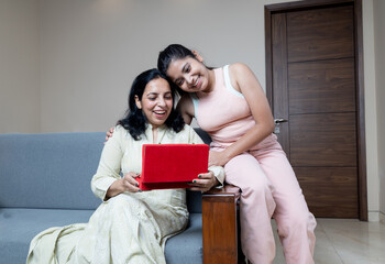 Indian teen daughter Giving Gift box to mother and congratulating her for mothers day