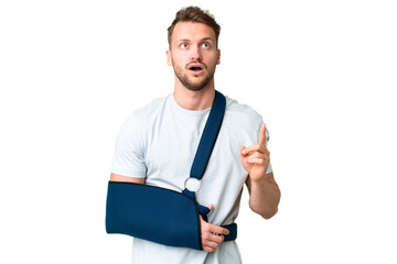 Young caucasian man with broken arm and wearing a sling over isolated chroma key background...