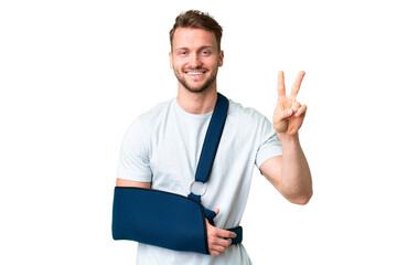Young caucasian man with broken arm and wearing a sling over isolated chroma key background smiling...