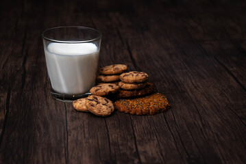 Comida. Vaso de leche con galleta, sobre mesa de madera.