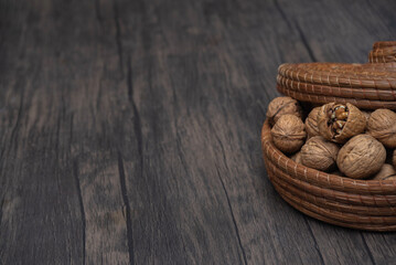 Comida. Nueces dentro de canasta sobre mesa de madera, apenas entrando al plano.