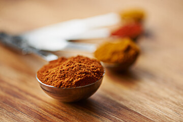 Spoons, spice and selection of powder to measure on kitchen table, turmeric and paprika for meal. Top view, condiments and options for spicy cooking in Indian culture, gourmet and food preparation