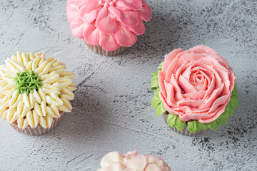 Colorful cupcakes with flower shaped decorations made with buttercream frosting. - obrazy, fototapety, plakaty