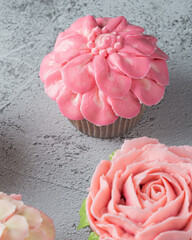 Colorful cupcakes with flower shaped decorations made with buttercream frosting.