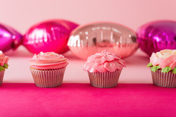 Colorful cupcakes on vibrant colored paper background. Decoration shaped like flowers with buttercream frosting.