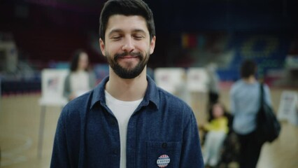 Happy male voter, US citizen after voting during Presidential Elections in the United States. Caucasian man with badge smiles and looks at camera standing at polling station. Civic duty. Portrait.