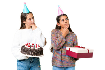 Friends girls holding gift and a birthday cake over isolated chroma key background thinking an idea...