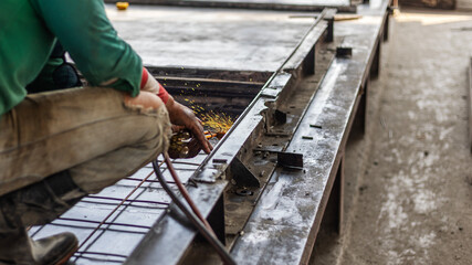 Worker with safety hat is welding pieces of metal mold together for precast floor production....