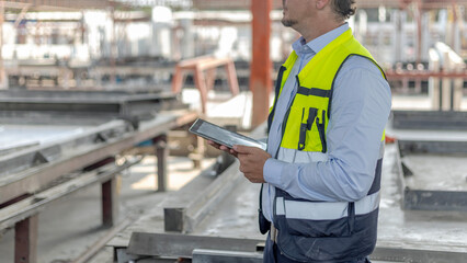 Civil engineer with safety hat using tablet or notebook to check the quality of readymade or precast floors in a factory