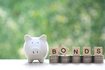 Bonds word on stack of coins money and piggy bank natural green background, Investments and Bonds...