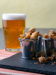 English pub snack of salted pork rind scratchings in miniature buckets with a glass of beer