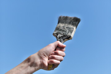 青空を背景に刷毛を持つ手
