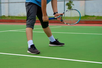Close up of tennis player legs with black shoe playing on tennis court. Tennis player in the...