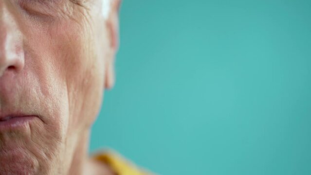 close-up of an elderly man chewing gum on a blue background. Body parts concept