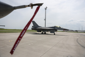 Fighter jet in parking position with red remove before flight ribbon attached