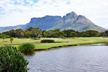 Mountain, landscape and water with grass at golf course in summer on holiday or vacation. Calm,...