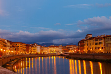 Panoramic view of the old town of Pisa and the Arno river at twilight, Italy. Night cityscape