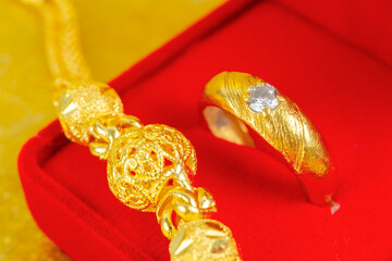 Gold ring on red velvet box on gold color background.